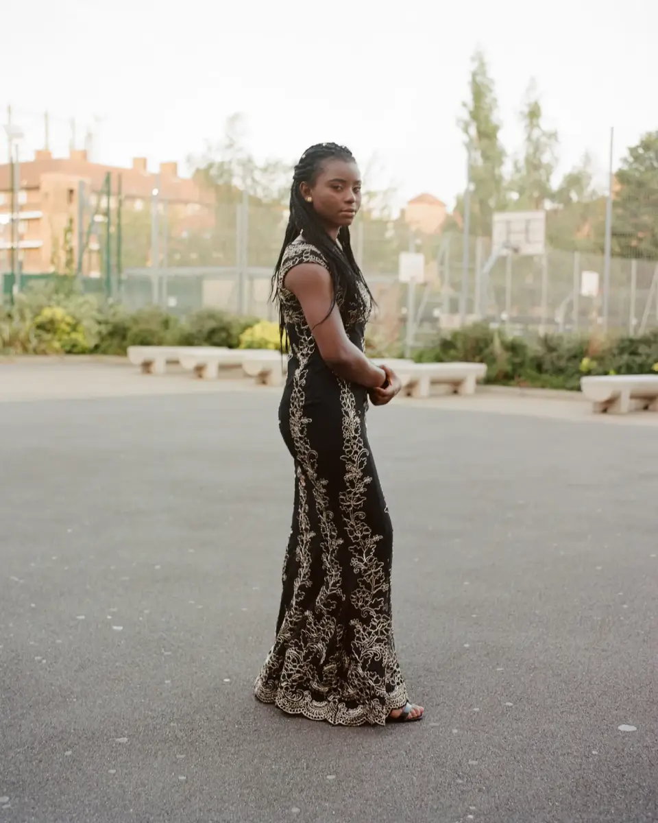 Een full body portret van een dame in een prom jurk op een Engels schoolfeest, ze staat op het schoolplein