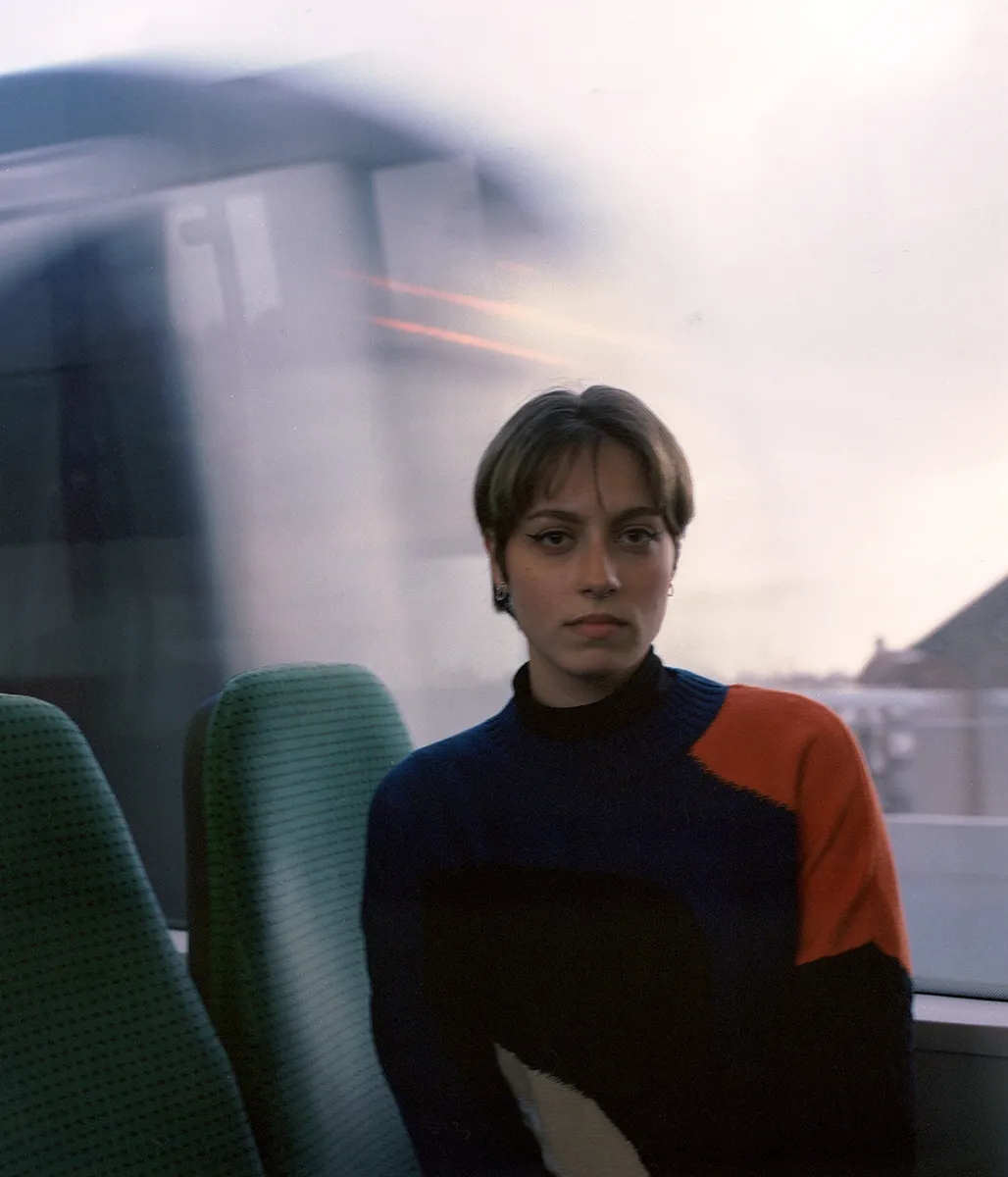 Een portret van een jonge vrouw met heel kort haar in een metro in Rotterdam, op de achtergrond zien we een andere metro in de bewegingsonscherpte voorbijkomen.