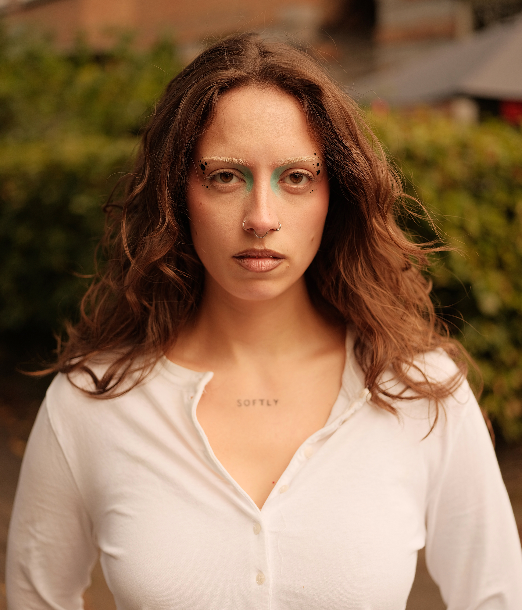 Een portret van een dame met uitgesproken make-up, ze kijkt recht in de camera en haar haren waaien mooi in de wind.