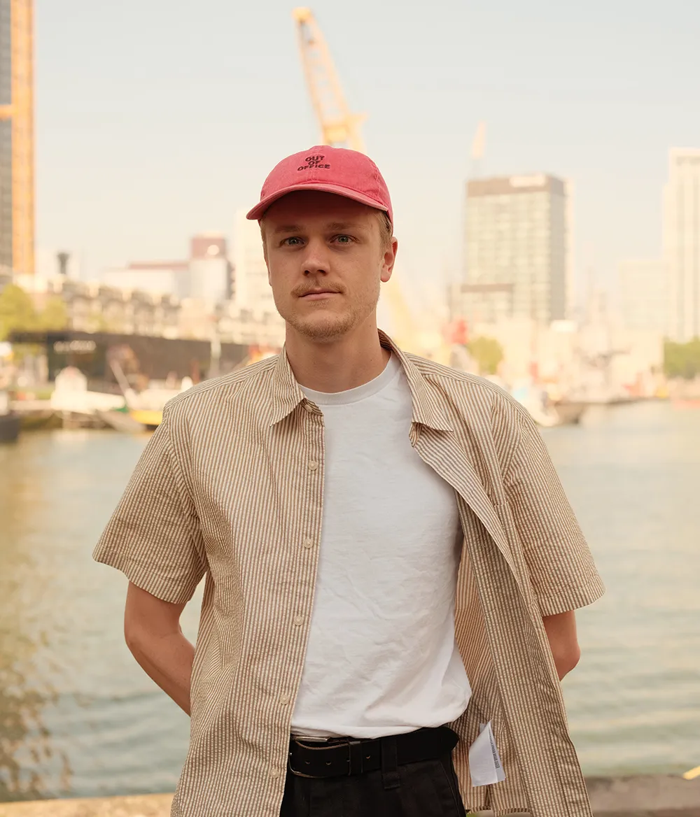 Portret van een jonge man die zich in de haven van Rotterdam bevindt, hij draagt en pet