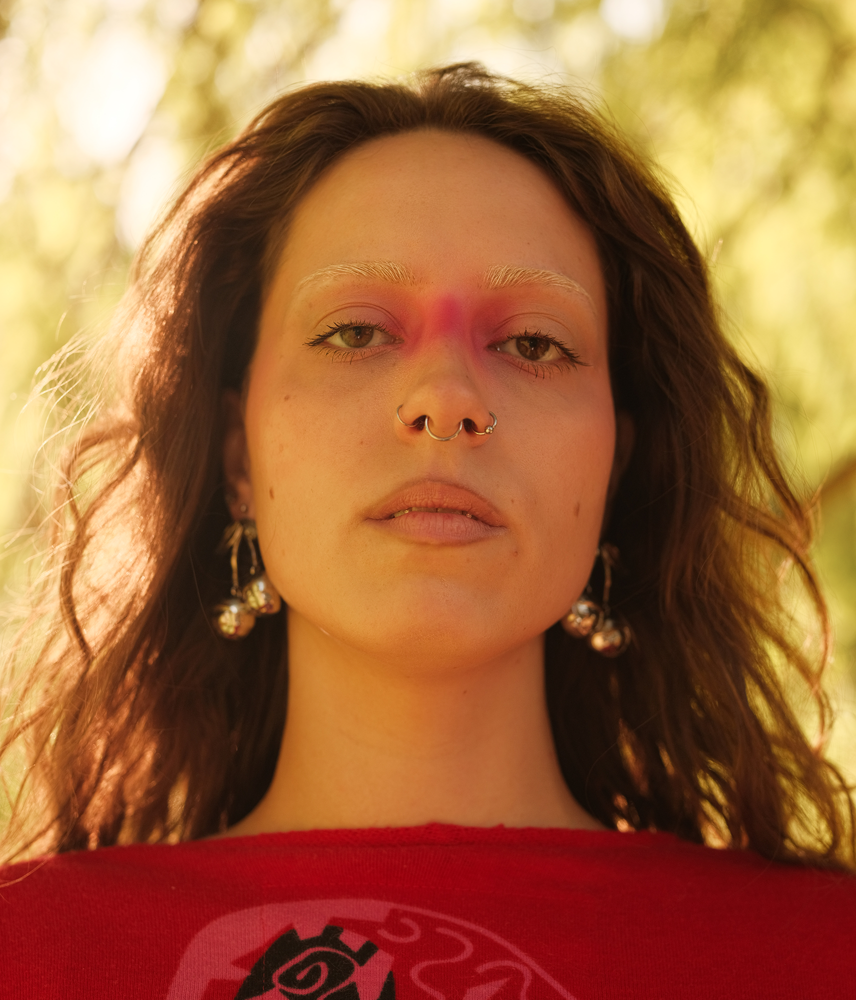 Een portret van een dame met uitgesproken make-up, gefotografeerd vanuit een laag perspectief. Ze kijkt recht in de camera.