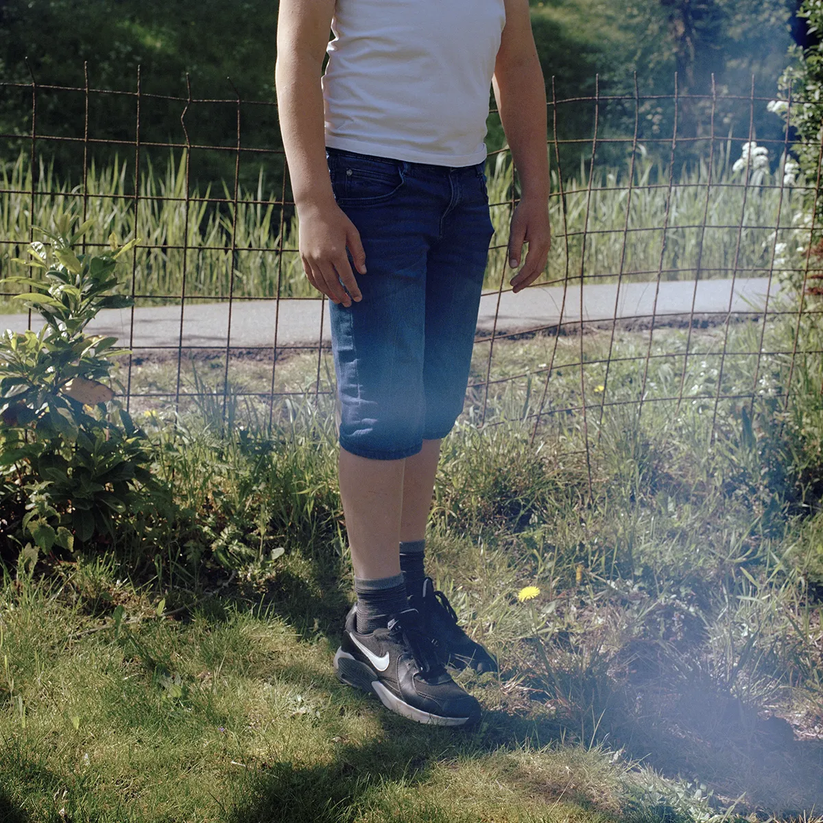 Een foto van de benen van een jongen die in het gras staat.
